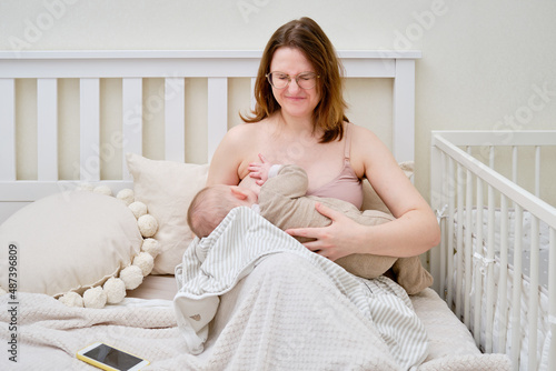 Pain and problems in a woman while breastfeeding a baby. Mother experiences discomfort while breastfeeding photo