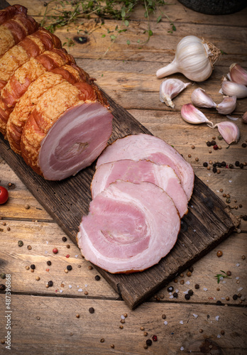 Smoked rolled bacon, roulade, rolled pancetta on wooden boards. Rustic composition with Polish cold cuts, meat products. photo