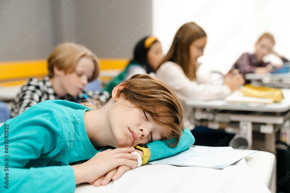 Ginger boy sleeping on desk during class at school