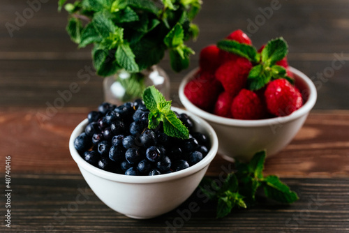 a variety of wild berries in a bowl on a wooden background. rasp