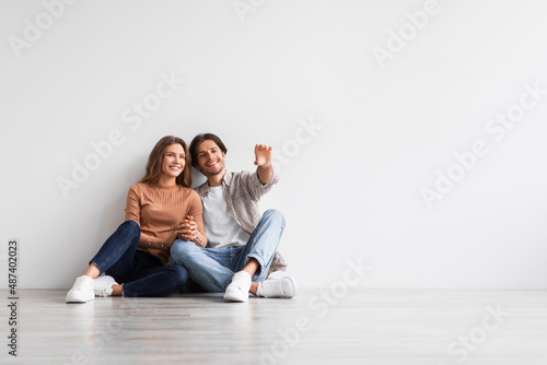 Obraz na plátne Cheerful dreaming young european family planning future interior, sit on floor o