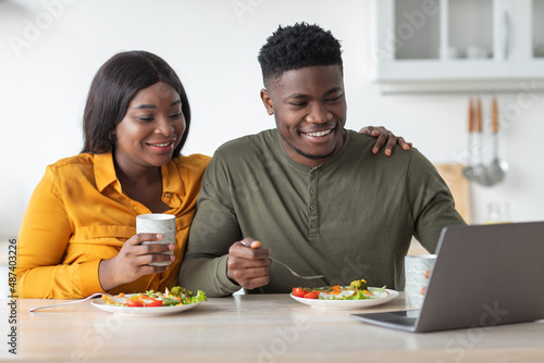 Happy African American Couple Watching Movie On Laptop Computer While Eating Breakfast