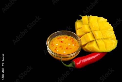 Cutted mango, chili pepper and mango chili sauce isolated on black background wiht copy space