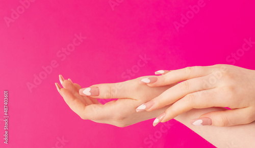 female hands with beautiful long nails with  manicure with  heart pattern on pink background
