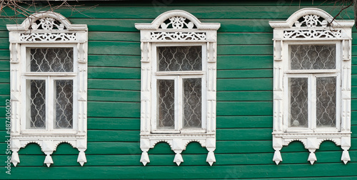 The old window of a rustic Russian wooden house is richly decorated with carvings in an old Russian city.