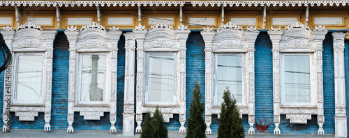 The old window of a rustic Russian wooden house is richly decorated with carvings in an old Russian city.