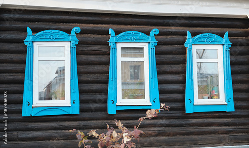 The old window of a rustic Russian wooden house is richly decorated with carvings in an old Russian city.