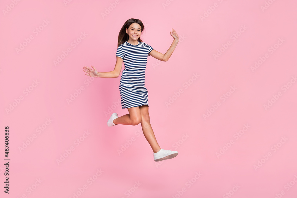 Photo of adorable pretty girl dressed striped dress jumping high empty space isolated pink color background