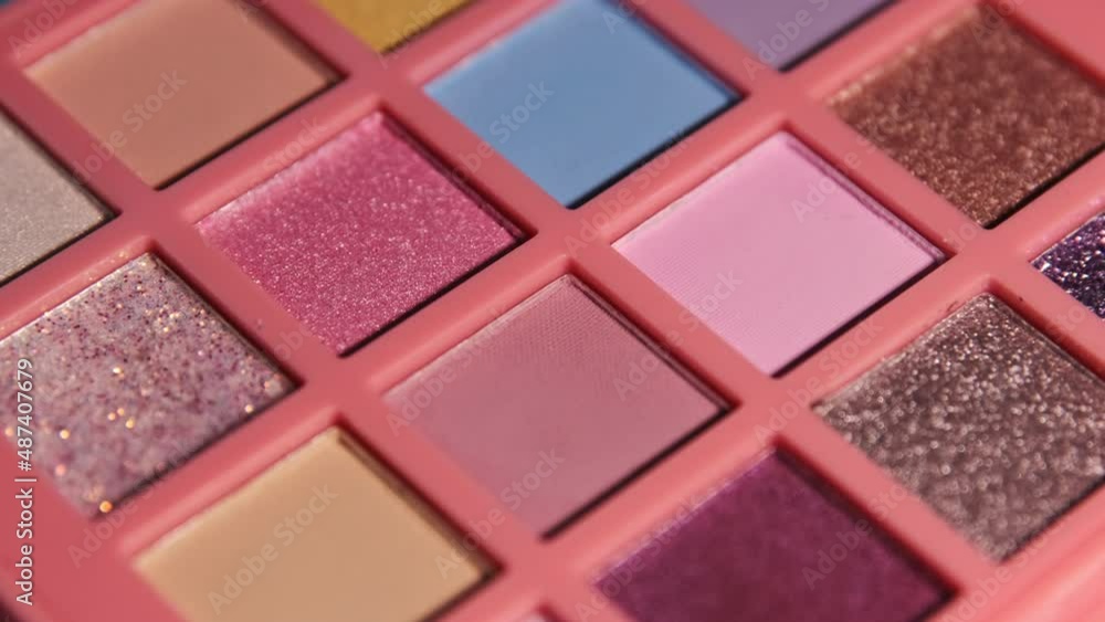 Make up eyeshadow multicolor palette illuminated by light and immersed in darkness. Colorful bright eye shadows set for visage. Rotation cosmetic background. Make up eyeshadow multicolor palette illuminated by light and immersed in darkness. Colorful bright eye shadows set for visage. Rotation cosmetic background.