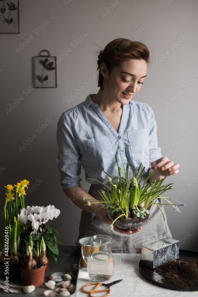 Smiling gardener with spring flowers at table Smiling gardener with spring flowers at table
