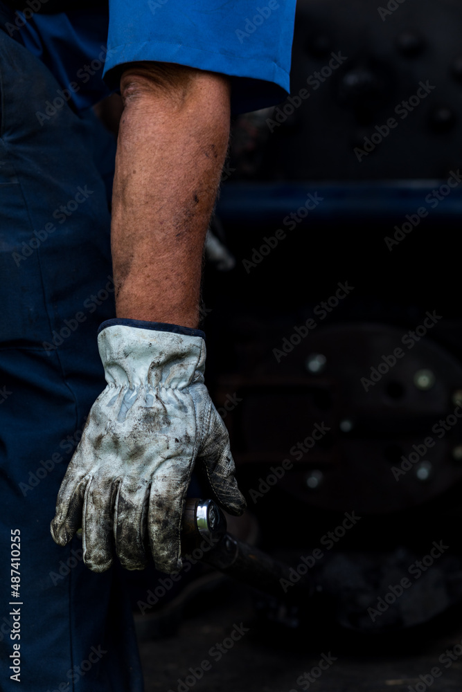Man's Arm with a Blue Short Sleeve and Dirty White Glove Holding a Lever Man's Arm with a Blue Short Sleeve and Dirty White Glove Holding a Lever