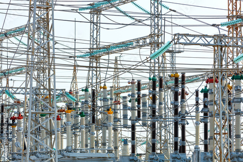A web of electrical wires and high-voltage dielectric insulators on the metal masts of a substation during daylight hours.