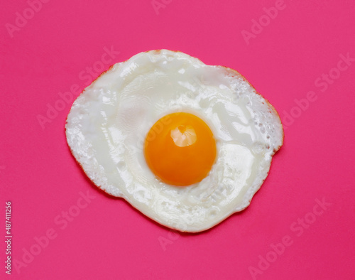 Fried egg yolk isolated on pink background.