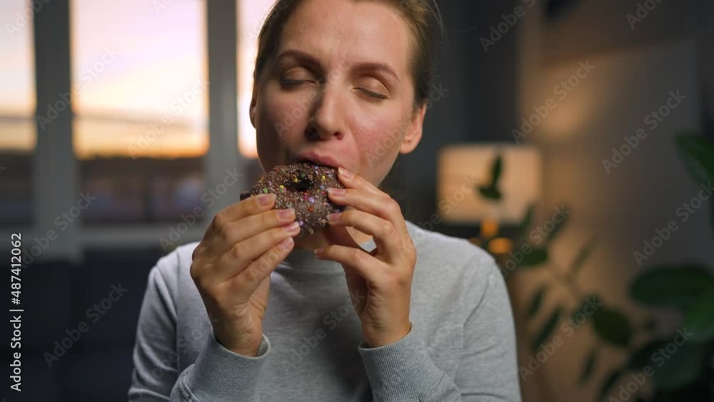 Sweet addiction concept. A woman eats a chocolate donut with morbid delight. Sweet addiction concept. A woman eats a chocolate donut with morbid delight.