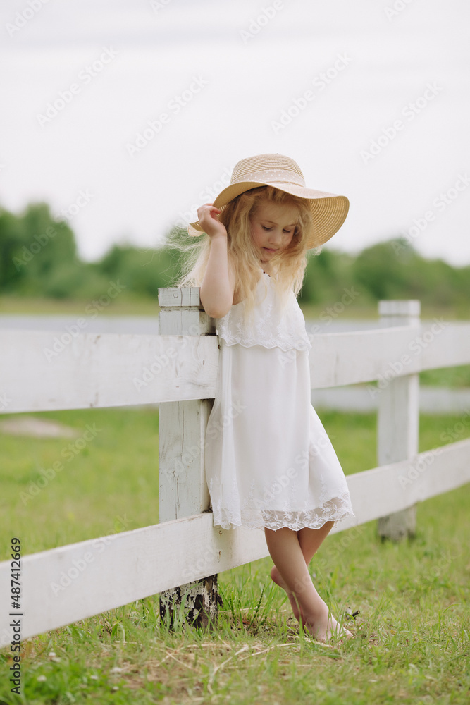 Beautiful little blonde girl on a ranch on a summer day.