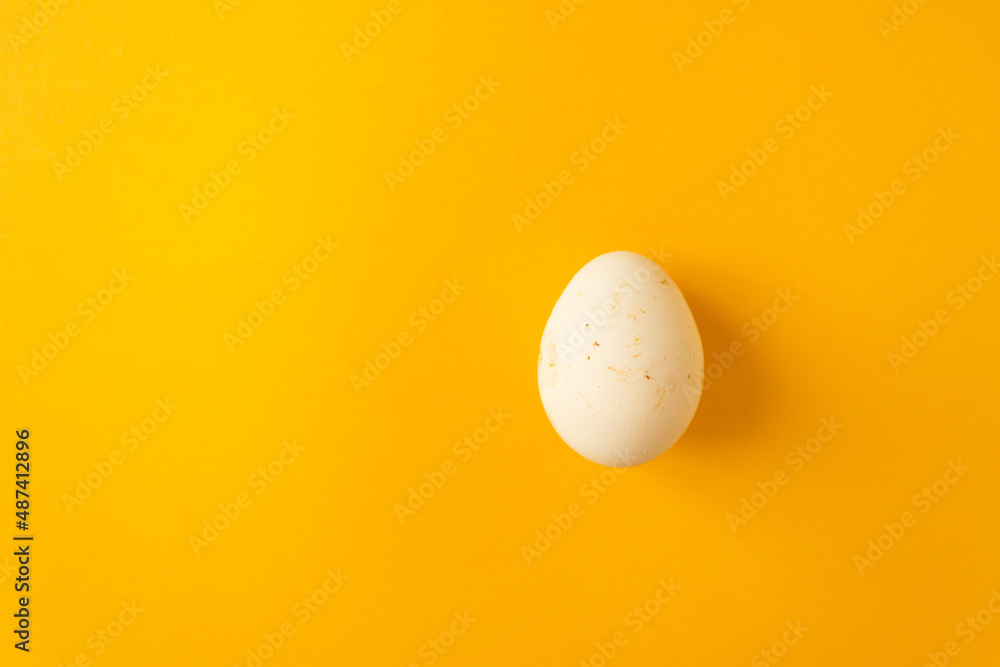 Single natural farm chicken egg isolated on yellow background. Easter holiday concept. Single natural farm chicken egg isolated on yellow background. Easter holiday concept.