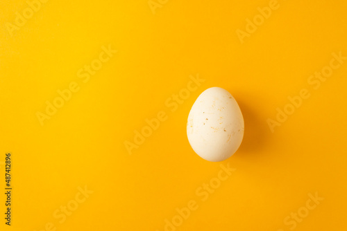 Single natural farm chicken egg isolated on yellow background. Easter holiday concept.