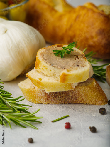 Macro shot. Foie gras on baguette slices, rosemary sprigs, garlic on a white background. Festive food. Recipes for restaurant and home cooking. Restaurant, hotel, cafe, banner.