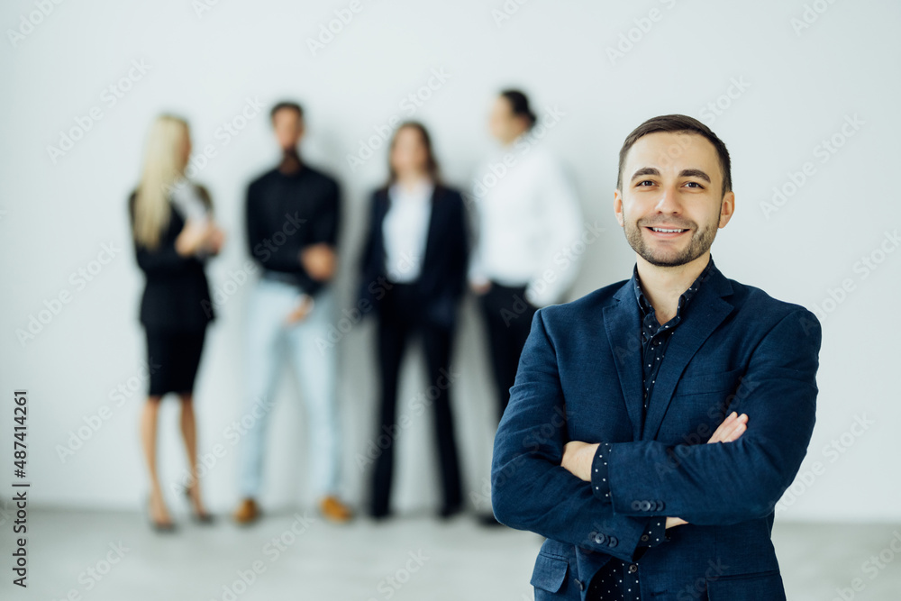 Handsome young businessman standing confident in the office in front of his team Handsome young businessman standing confident in the office in front of his team