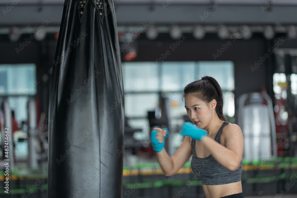 Female boxer hitting a huge punching bag at a boxing studio. Woman boxer training hard.
