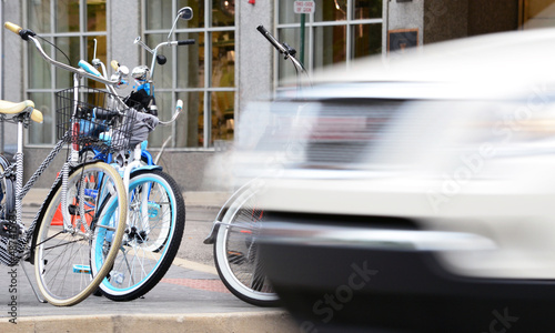 Parked bicycles on a street with a moving car