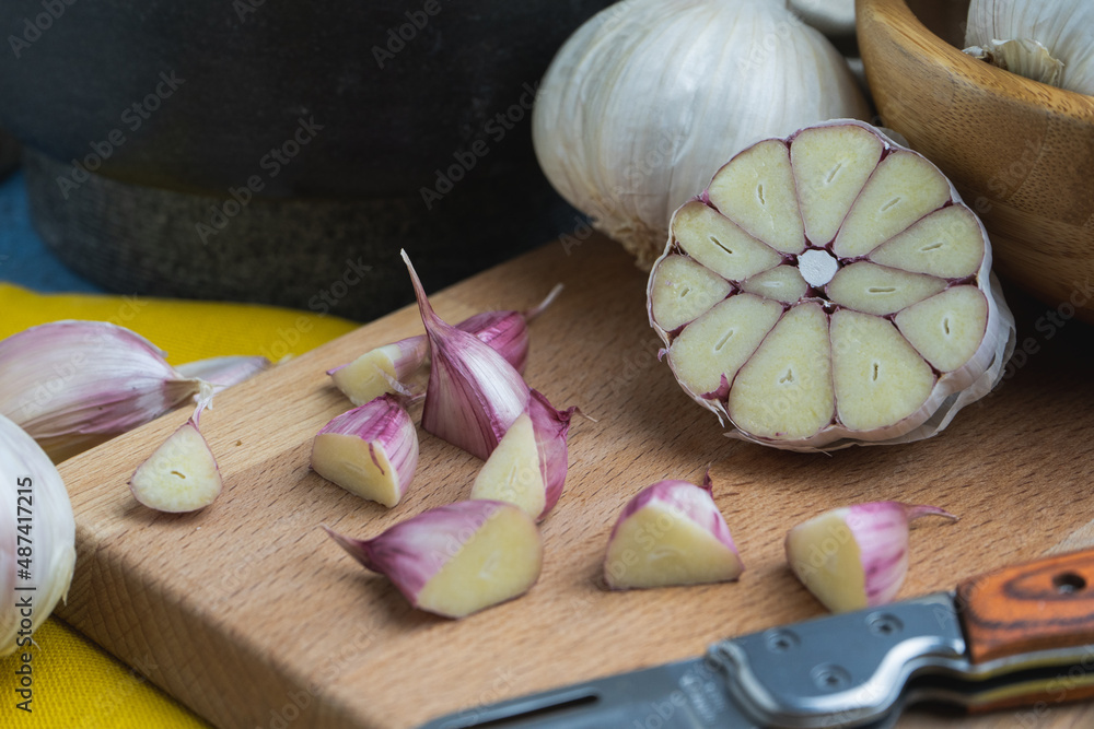 Cabeza de ajos cortada por la mitad junto a unos dientes de ajo Stock