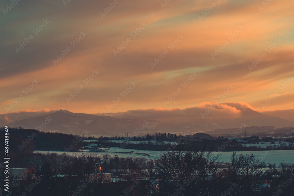 colorful sunset clouds over the countryside in czech republic with snow and mountains in the background on a winter day colorful sunset clouds over the countryside in czech republic with snow and mountains in the background on a winter day