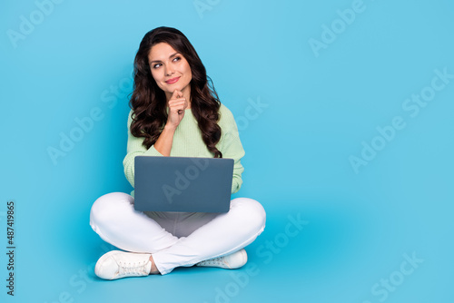 Portrait of attractive curious minded cute woman sitting using laptop making decision copy space isolated over bright blue color background © deagreez
