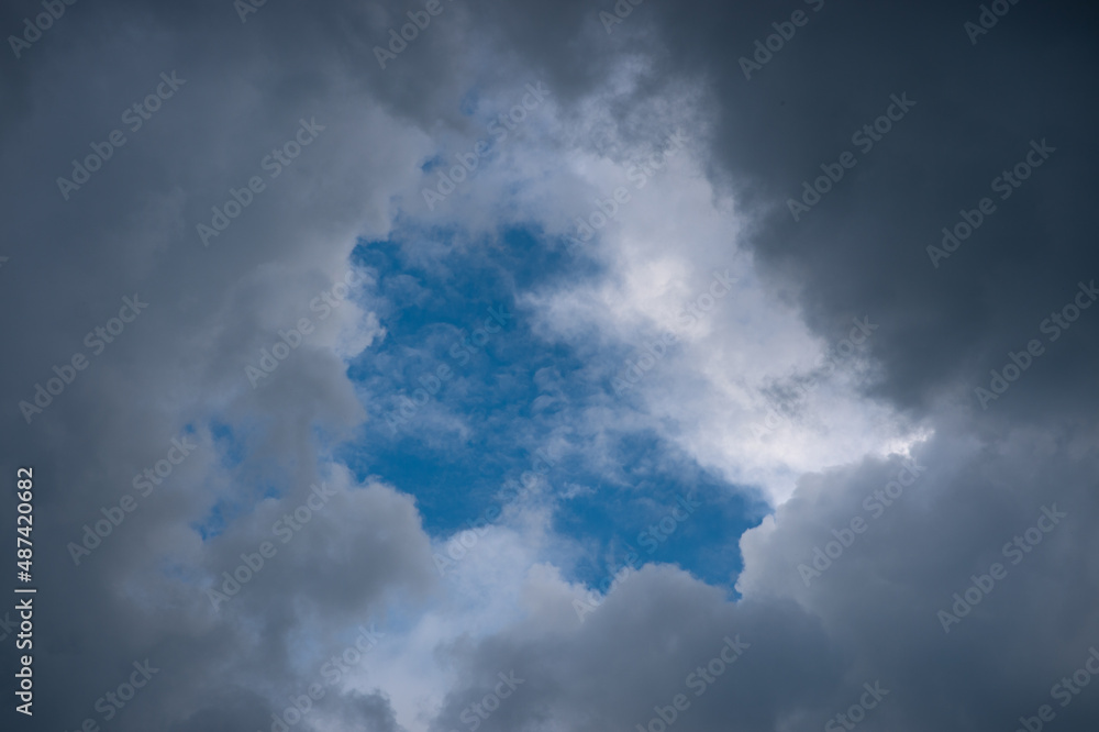Obraz premium Overhanging dark leaden and heavy clouds surround the blue sunset sky