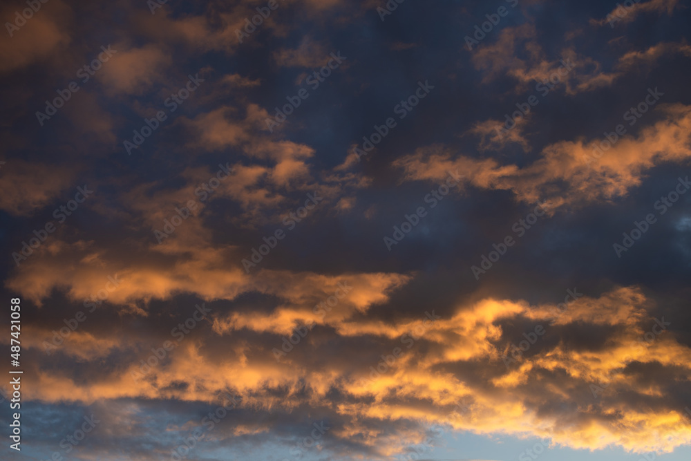 Dense painted clouds at sunset against a blue sky