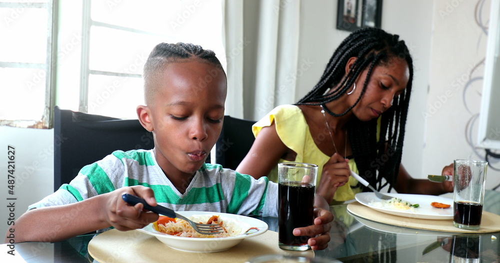 Black family eating lunch, little boy and teenage girl eating meal