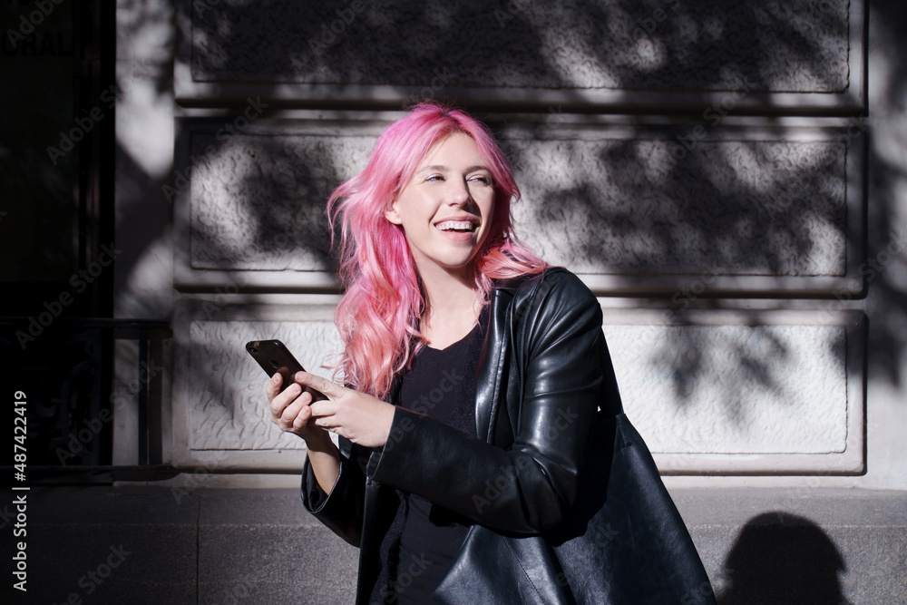 Obraz premium happy girl in rocker look with cell phone in hand outdoors