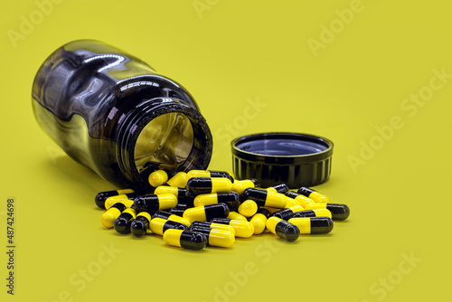 Fototapet bottle of black and yellow pills on yellow background, caseia aor caffeine pills