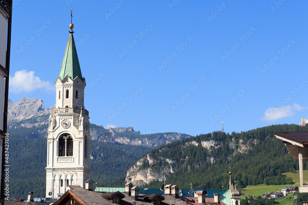 Basilica church steeple and mountain panorama view in Cortina d'Ampezzo, Italy