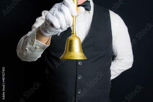 Closeup of Gold Serving Bell Held by Butler or Waiter. Concept of Service Industry and Professional Hospitality.