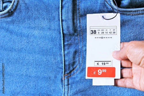 Close up hand holding promotion price tag on blue jean. photo