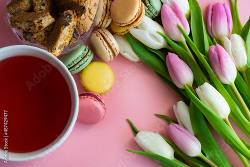 flat lay with tulips, tea and sweets on pink background