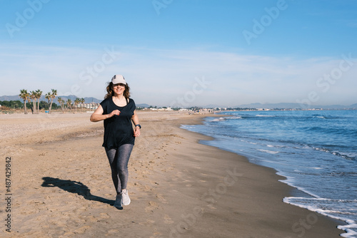 Baby Bommer woman smiling running on the beach photo