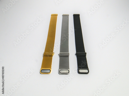 Three pieces of magnetic watch bracelets made of knitted metal stand on a white background, close-up