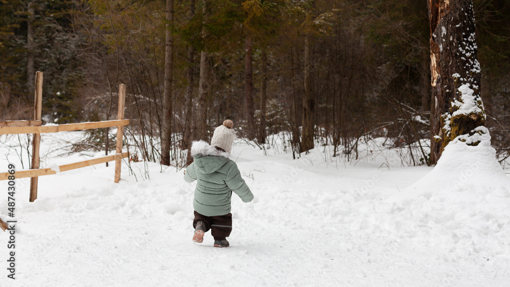 Happy traveling baby toddler spending time outdoors. Winter in the park or forest.