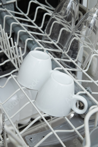 White dishes in the dishwasher. Homework with dishwasher concept