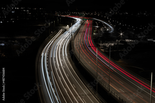 Cars and trucks driving at night over a bridge on a higly trafficated road in the middle of a city over a river photo