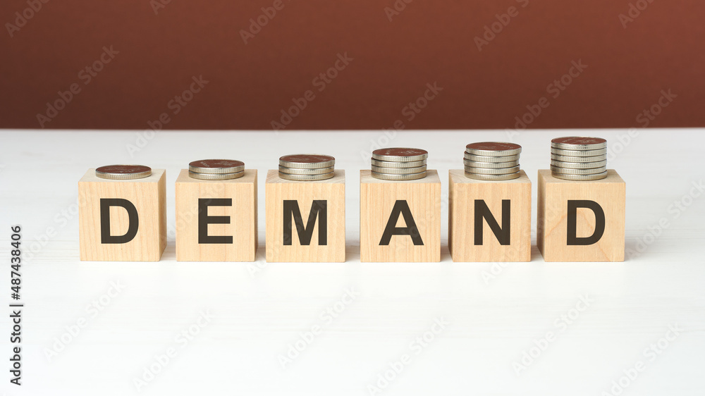 demand text on wooden blocks with coins on brown background demand text on wooden blocks with coins on brown background