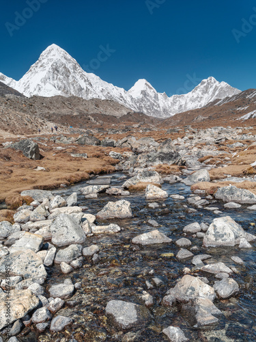 view to snow peaks of Himalaya and wild mountain creek under blue sky in Nepal