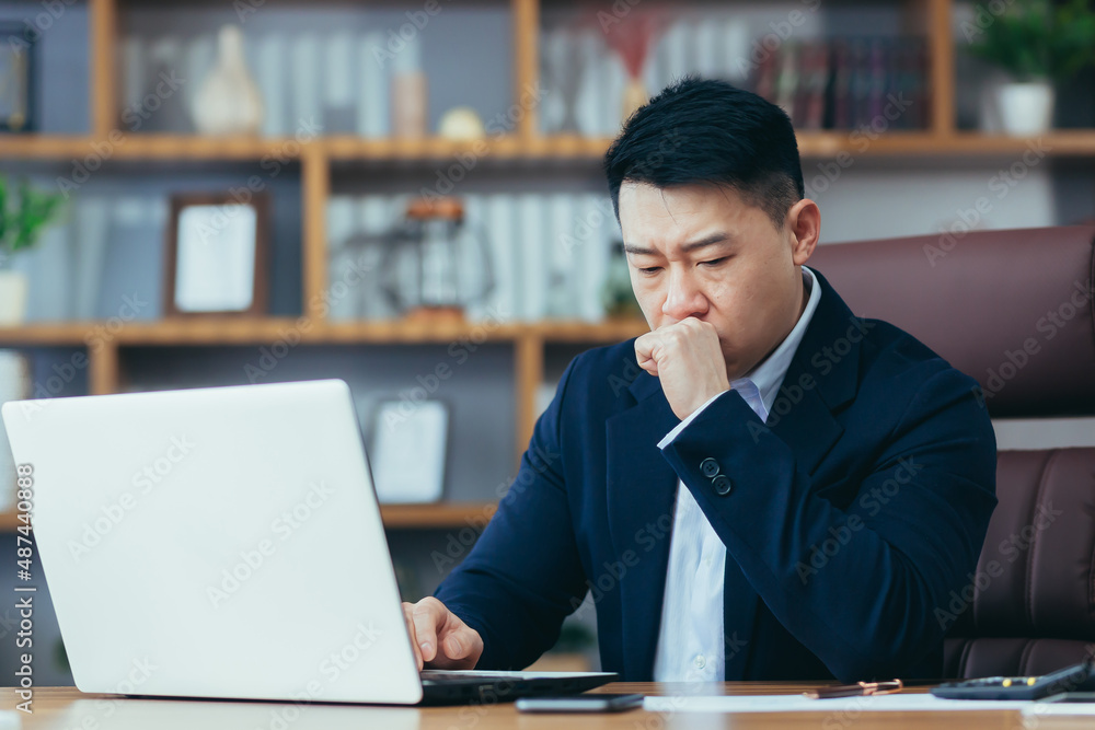 Obraz premium Sick asian businessman working on laptop in office, man coughing