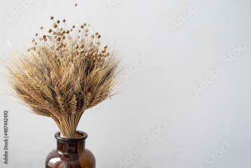 A simple brown vase with a bouquet of wheat. Home decor. Place for your text.