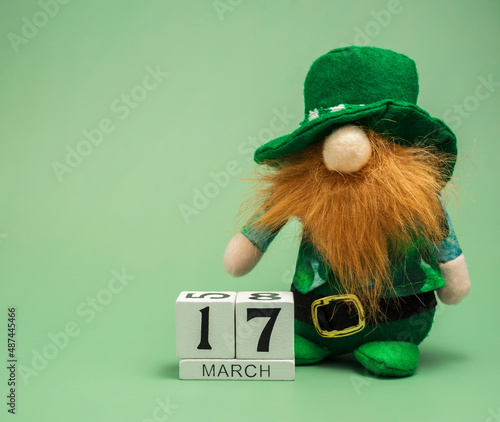 Irish gnome or leprechaun in a green suit on a green background. Composition for St. Patrick's Day