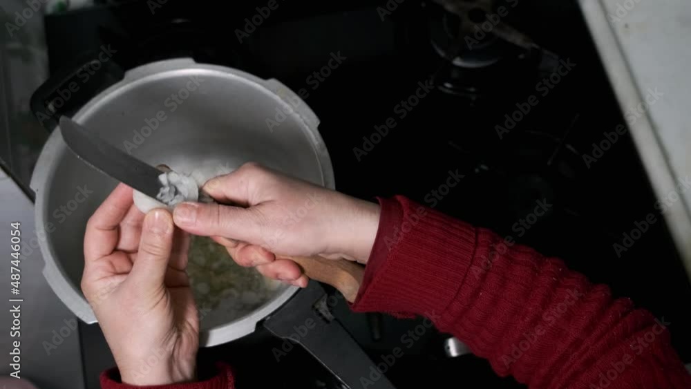 The woman, with only her hands visible, is chopping onions with a knife. top angle The woman, with only her hands visible, is chopping onions with a knife. top angle