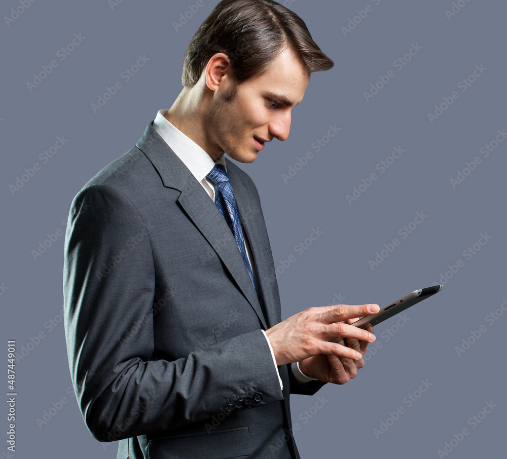 businessman using tablet computer in front of grey background businessman using tablet computer in front of grey background