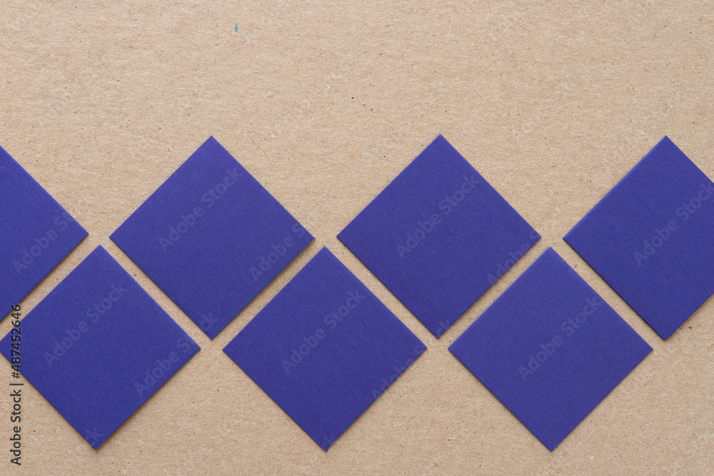 Fototapeta premium blue paper squares on a cardboard background